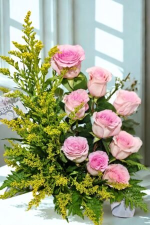 Arreglo floral de condolencias con rosas rosadas, solidago amarillo y follajes verdes en diseño elegante para expresar apoyo y respeto.