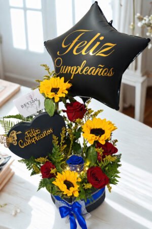 Arreglo floral de cumpleaños con girasoles, rosas rojas, rosa preservada azul iluminada, globo Feliz Cumpleaños y caja decorativa.