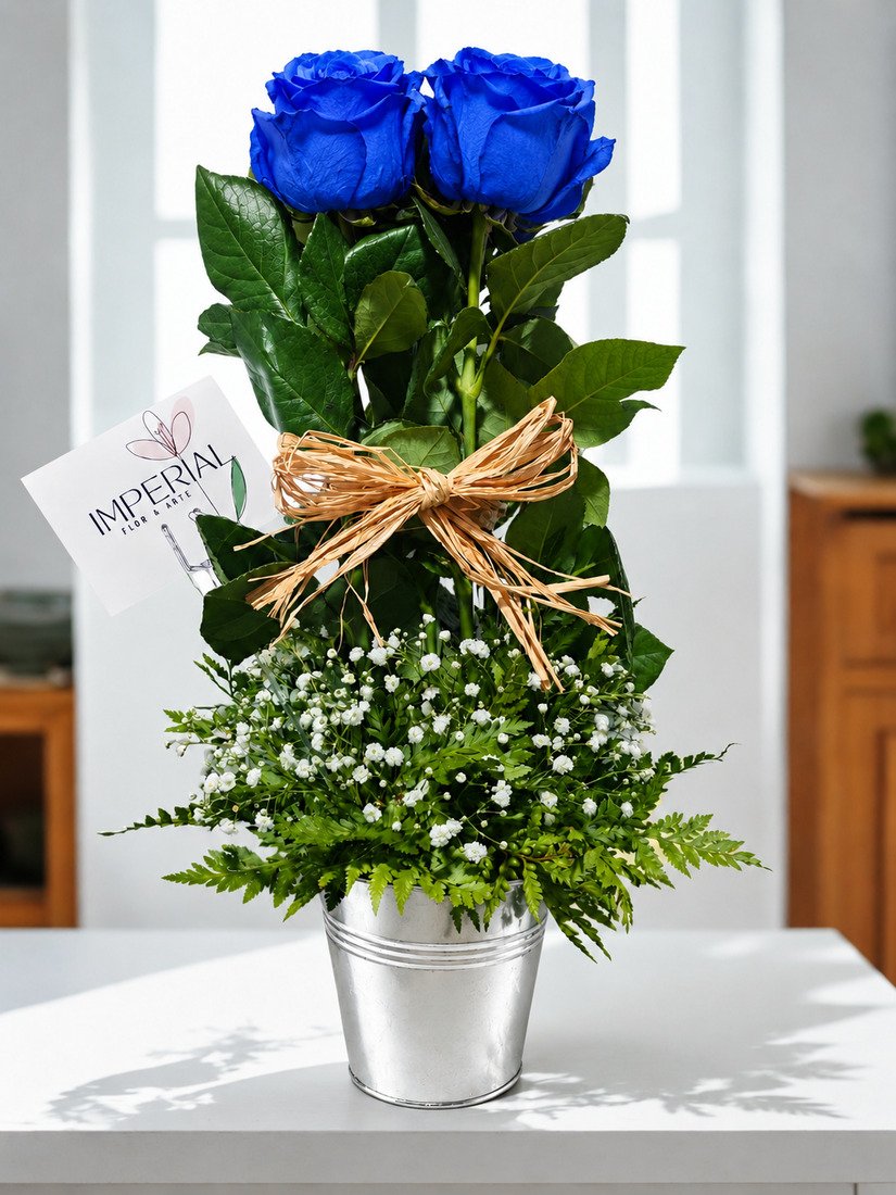 Arreglo floral de cinco rosas azules con gypsophila, follaje natural y lazo decorativo en base elegante.