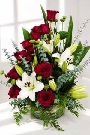 Plafón floral con 12 rosas rojas, 3 varas de liliums blancos, eucalipto, mable estilo pinoquio y follaje verde en elegante base decorativa.