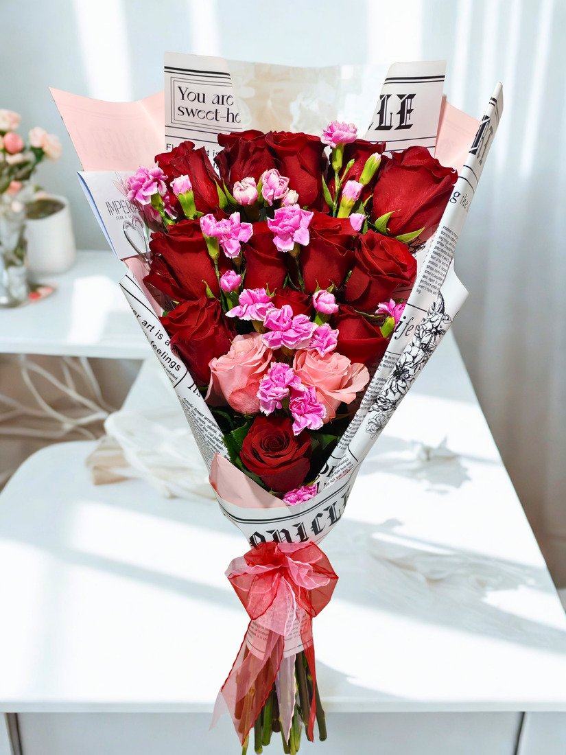 Ramo Promesa de Amor con 15 rosas premium, 13 rosas rojas y 2 rosas rosadas, acompañado de 8 varas de mini claveles y elegante papel coreano.